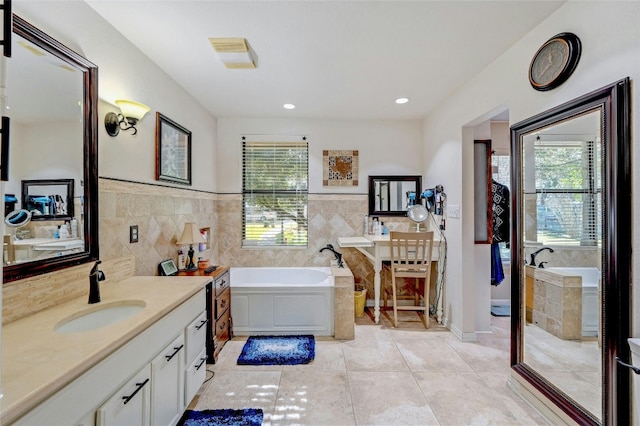 bathroom with a bathing tub, vanity, tile patterned floors, and tile walls