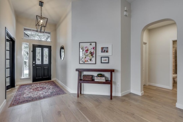 entryway featuring light hardwood / wood-style floors, a high ceiling, and an inviting chandelier