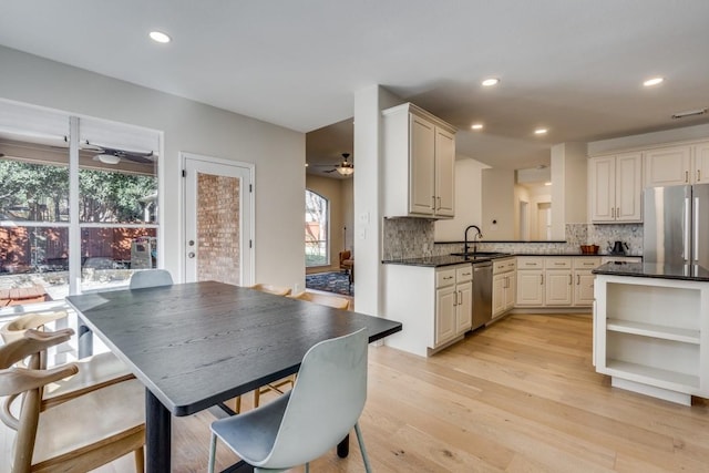 kitchen with backsplash, sink, appliances with stainless steel finishes, light hardwood / wood-style floors, and kitchen peninsula