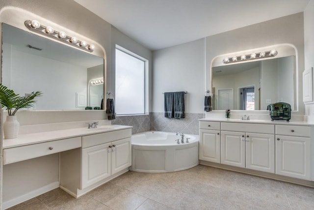 bathroom with a bathing tub, vanity, and tile patterned floors