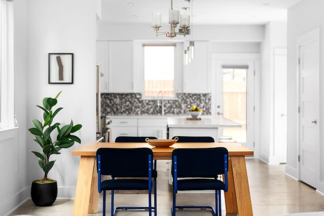 kitchen with sink, an inviting chandelier, backsplash, pendant lighting, and white cabinets