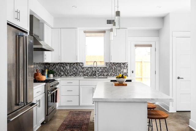 kitchen with high quality appliances, sink, decorative light fixtures, a kitchen island, and white cabinetry