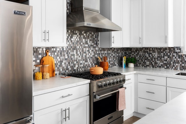 kitchen featuring backsplash, white cabinetry, wall chimney exhaust hood, and appliances with stainless steel finishes