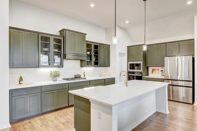 kitchen featuring stainless steel appliances, an island with sink, tasteful backsplash, and pendant lighting