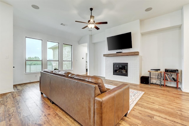 living room with a fireplace, light hardwood / wood-style floors, and ceiling fan