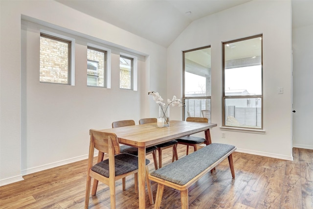 dining space featuring vaulted ceiling and light wood-type flooring