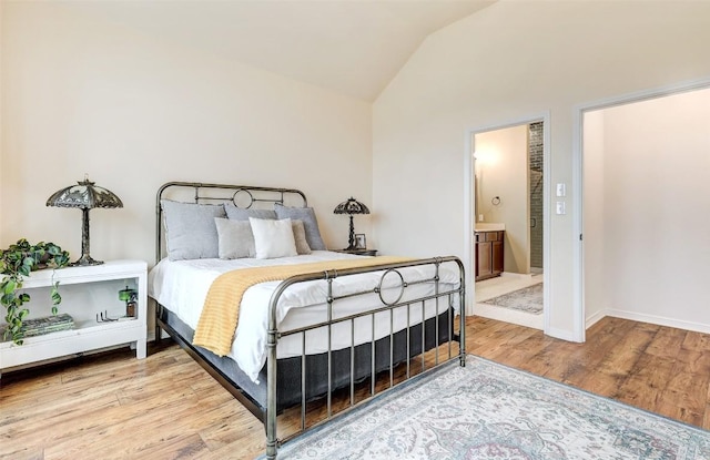 bedroom featuring wood-type flooring, connected bathroom, and vaulted ceiling