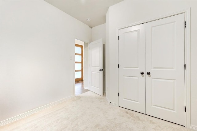 unfurnished bedroom featuring light carpet and a closet