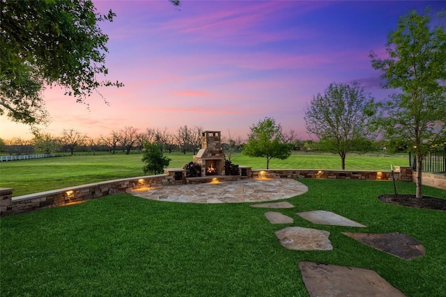 yard at dusk with an outdoor stone fireplace