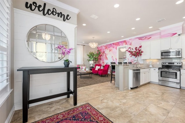 kitchen featuring crown molding, white cabinets, pendant lighting, and appliances with stainless steel finishes