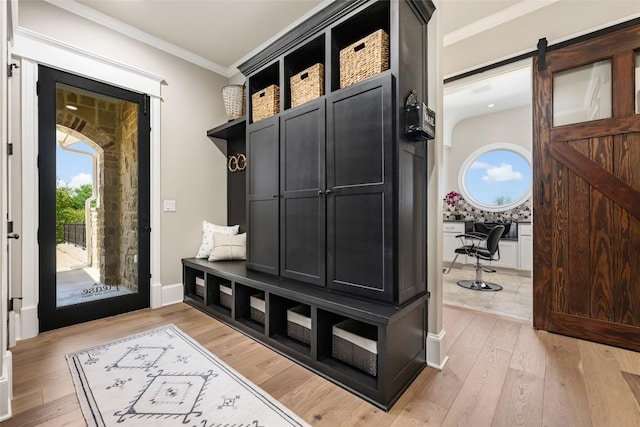 mudroom featuring a barn door, light hardwood / wood-style floors, and crown molding