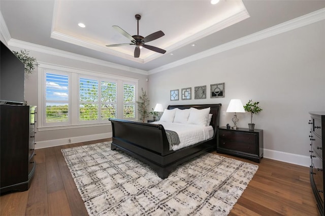 bedroom featuring hardwood / wood-style flooring, a raised ceiling, ceiling fan, and crown molding