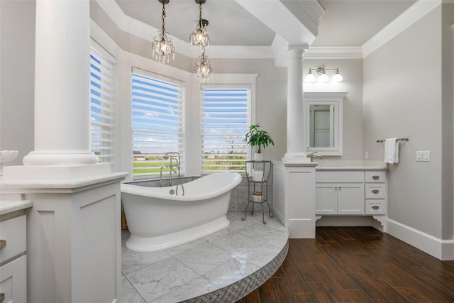 bathroom with a washtub, vanity, decorative columns, and crown molding