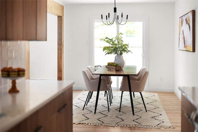 dining space with light hardwood / wood-style flooring and an inviting chandelier