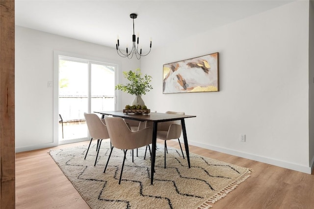 dining area with light hardwood / wood-style floors and a notable chandelier