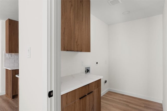 laundry room featuring electric dryer hookup, cabinets, washer hookup, and light wood-type flooring