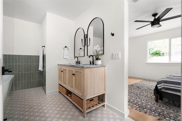 bathroom with ceiling fan, vanity, and tile walls