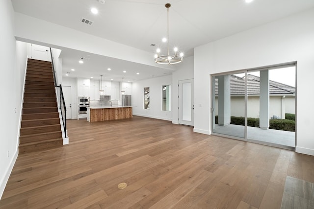 unfurnished living room with light wood-type flooring, a chandelier, and sink