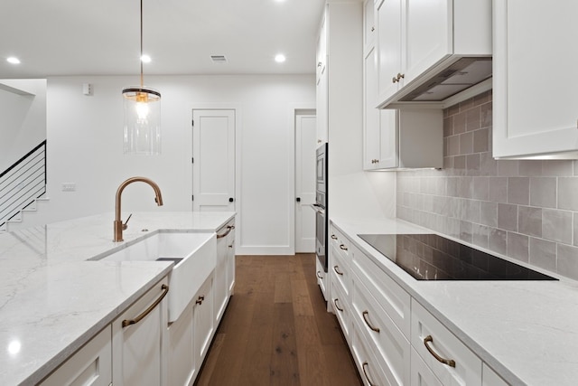 kitchen featuring stainless steel appliances, hanging light fixtures, custom range hood, light stone countertops, and white cabinets