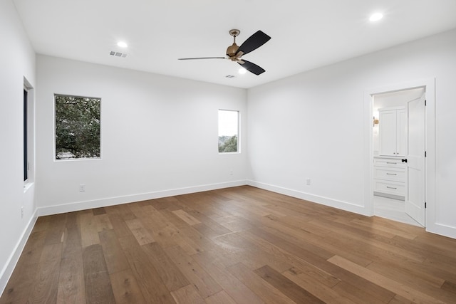 unfurnished bedroom with ceiling fan, ensuite bathroom, and hardwood / wood-style floors