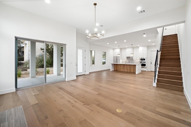 unfurnished living room featuring a chandelier, light hardwood / wood-style floors, and sink