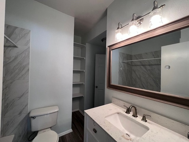 bathroom featuring a tile shower, vanity, and toilet