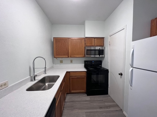 kitchen featuring dishwasher, dark wood-type flooring, white refrigerator, sink, and black range with electric cooktop