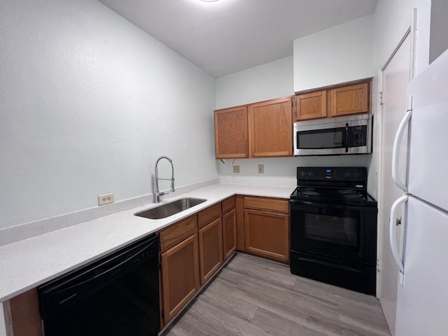 kitchen featuring black appliances, light wood-type flooring, and sink