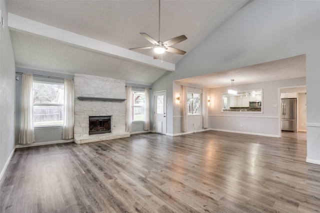 unfurnished living room with beamed ceiling, a fireplace, wood-type flooring, high vaulted ceiling, and ceiling fan