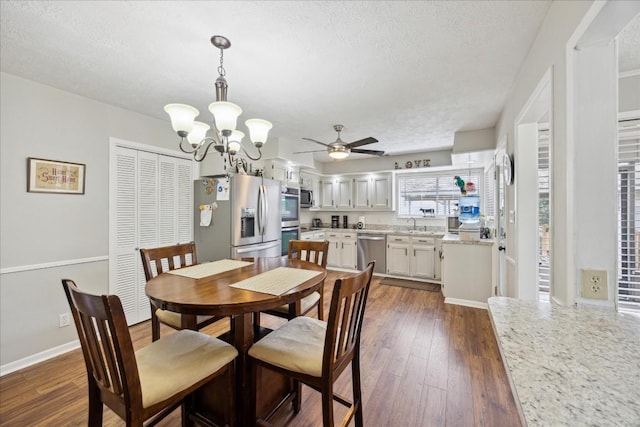 dining space featuring sink, ceiling fan with notable chandelier, dark hardwood / wood-style flooring, and a textured ceiling