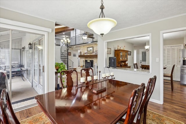 dining space featuring dark wood-type flooring, ceiling fan, ornamental molding, a textured ceiling, and a fireplace