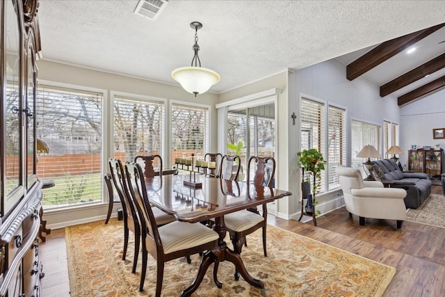 dining space featuring vaulted ceiling with beams, a textured ceiling, and hardwood / wood-style flooring