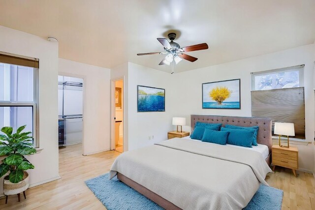 bedroom featuring light hardwood / wood-style floors, ensuite bath, and ceiling fan