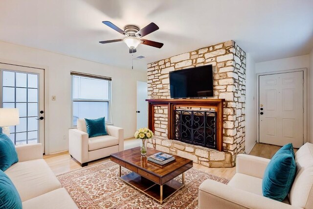 living room with ceiling fan, light hardwood / wood-style floors, and a fireplace