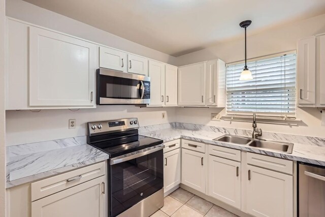 kitchen featuring white cabinetry, appliances with stainless steel finishes, sink, and hanging light fixtures