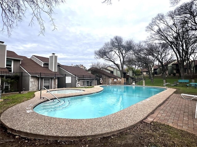 pool featuring a community hot tub, a patio area, fence, and a residential view