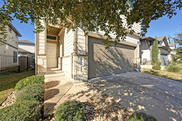 view of front of house with a garage, driveway, stone siding, and fence