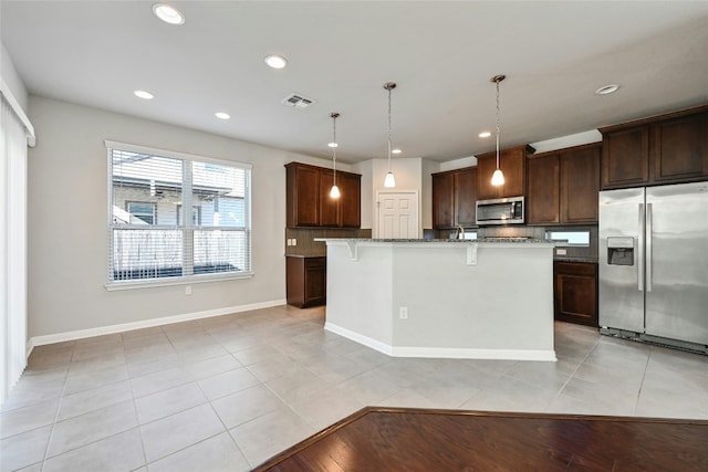 kitchen featuring light tile patterned floors, dark stone counters, appliances with stainless steel finishes, a breakfast bar area, and recessed lighting