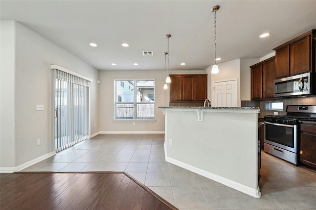 kitchen with light tile patterned floors, visible vents, appliances with stainless steel finishes, a breakfast bar, and stone counters