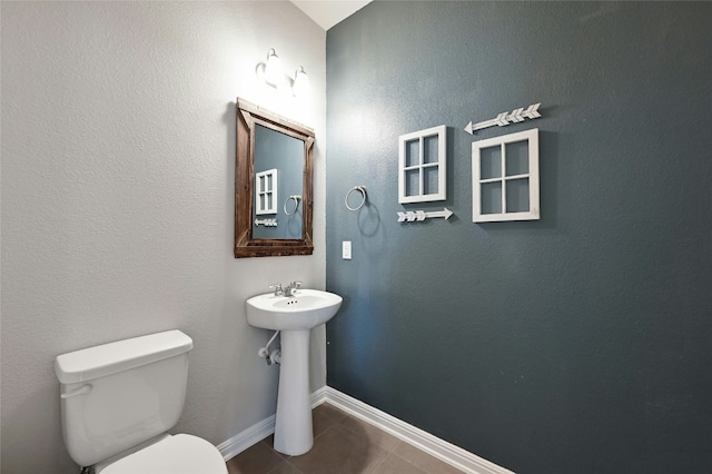 bathroom with baseboards, a sink, toilet, and tile patterned floors