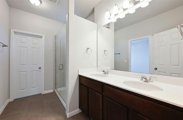 bathroom featuring a stall shower, double vanity, a sink, and tile patterned floors