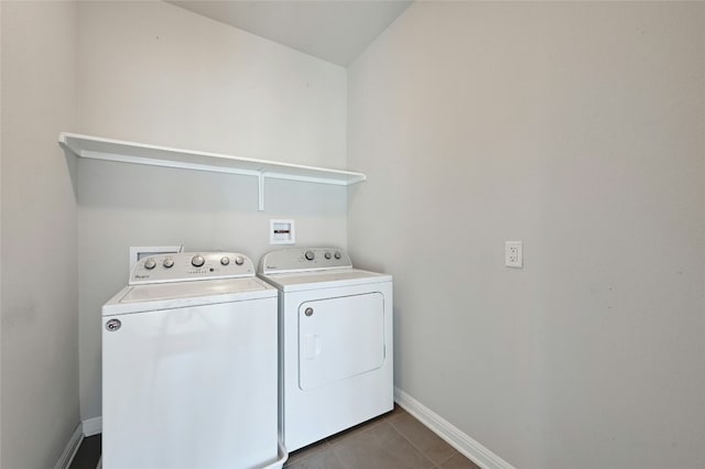 washroom featuring laundry area, dark tile patterned floors, baseboards, and washing machine and clothes dryer