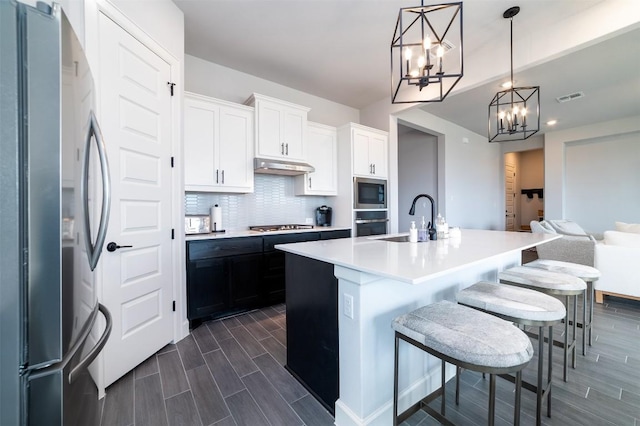 kitchen with white cabinetry, sink, decorative light fixtures, a center island with sink, and appliances with stainless steel finishes