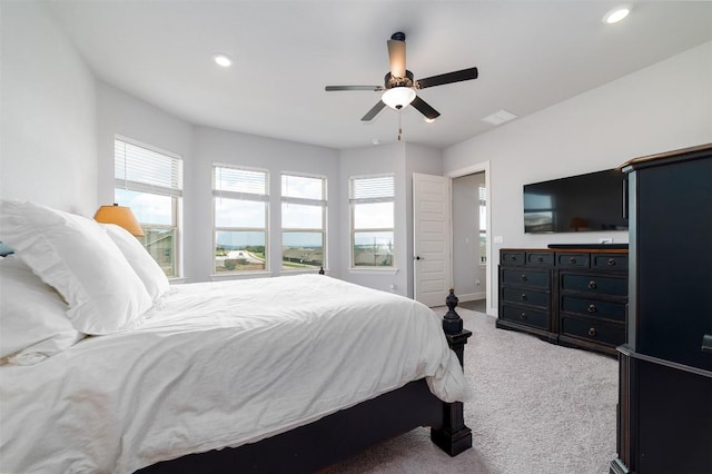 bedroom with multiple windows, ceiling fan, and light carpet