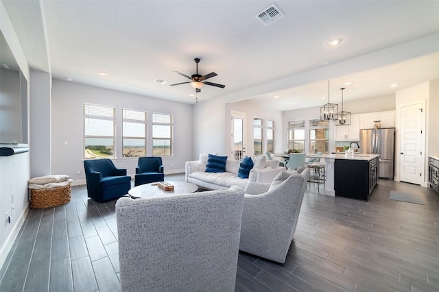 living room with ceiling fan with notable chandelier and sink