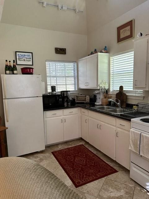 kitchen with white cabinetry, light tile patterned floors, track lighting, and white appliances