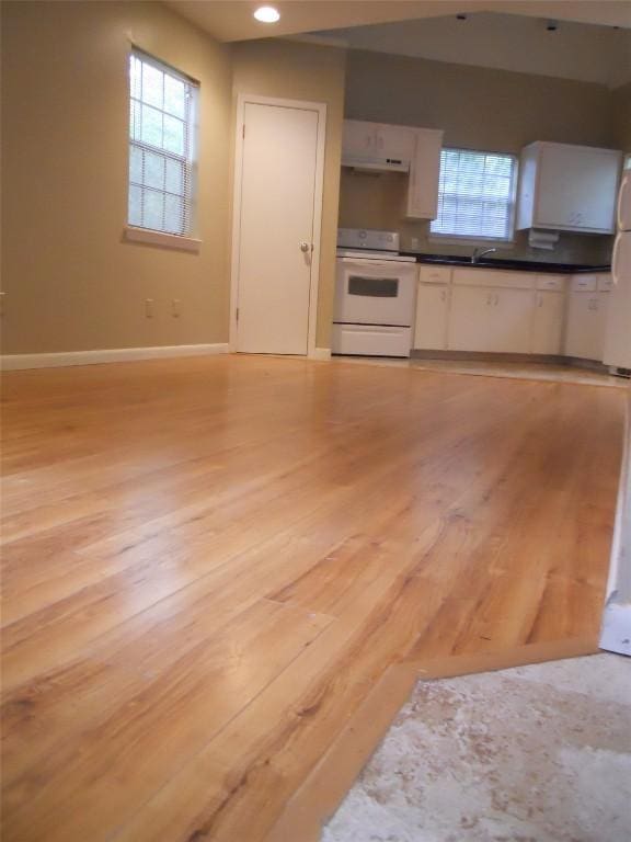 kitchen with white cabinets, white stove, and light hardwood / wood-style floors