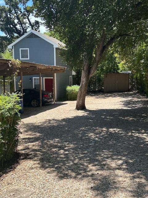 view of front of home with a carport and a storage unit