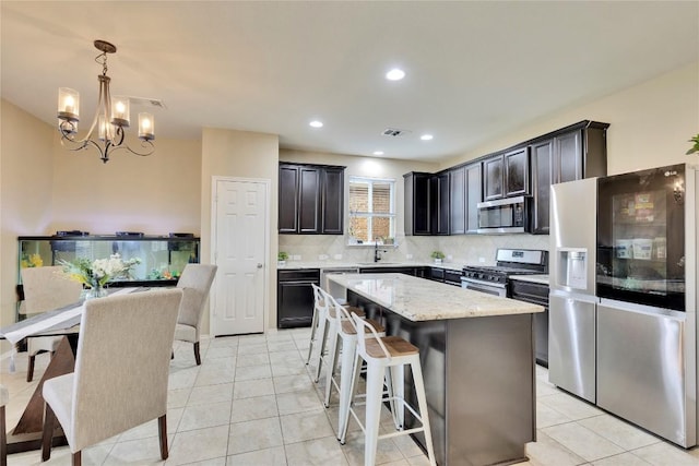 kitchen featuring stainless steel appliances, sink, a chandelier, a kitchen island, and hanging light fixtures