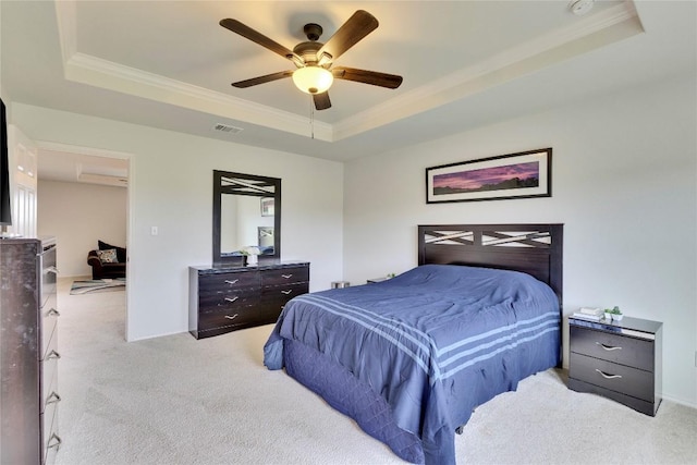 bedroom featuring ceiling fan, light colored carpet, crown molding, and a tray ceiling